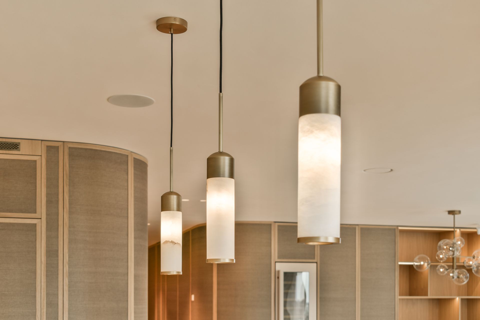 Modern interior with three hanging pendant lights and light wood cabinetry