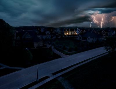 Dark neighborhood under stormy sky with lightning striking in the distance