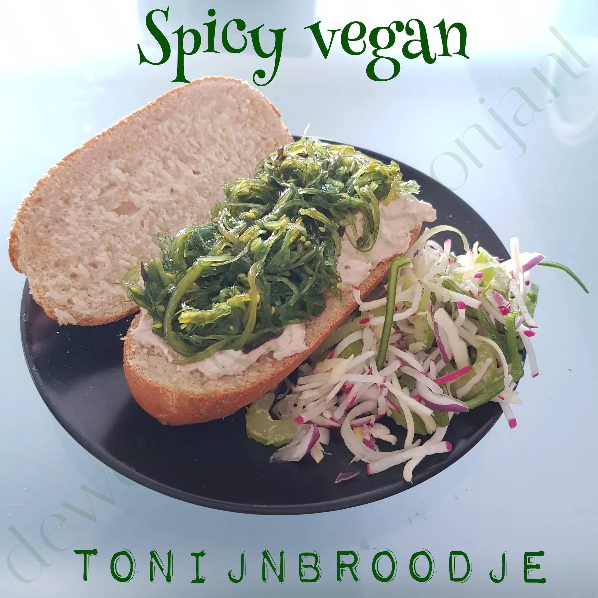 Veganistisch broodje met zeewier, geserveerd met koolsalade, op een zwart bord, lichte achtergrond.