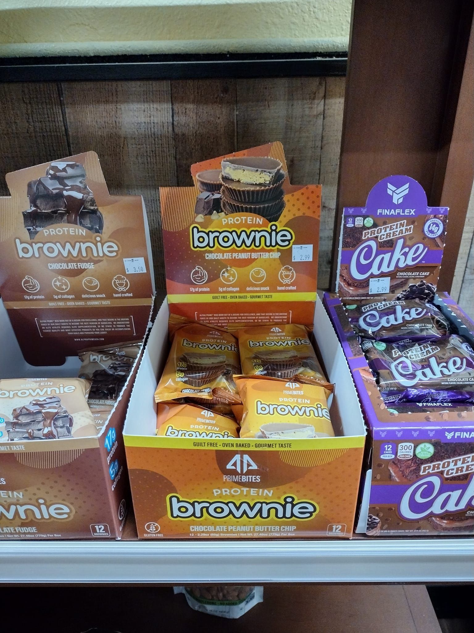 Shelves display packaged brownie and cake snacks in cardboard boxes, featuring brown, orange, and purple packaging.