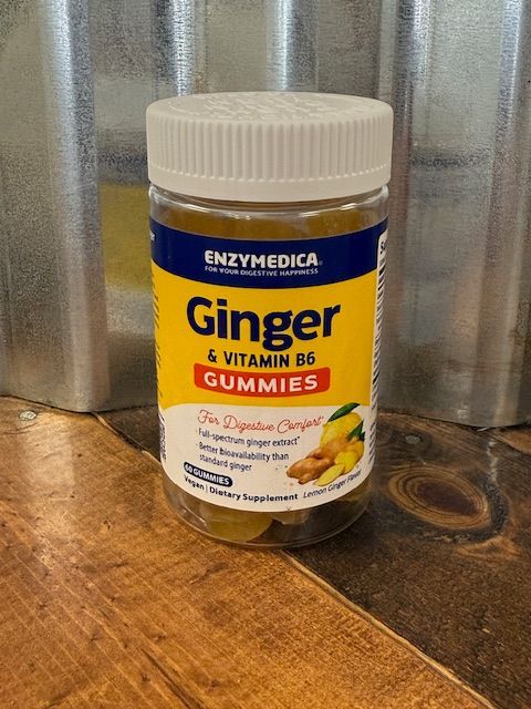 Jar of Enzymedica Ginger & Vitamin B6 gummies on a wooden surface, with a galvanized metal background.