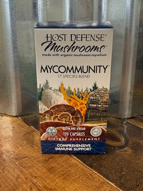 Box of Host Defense MyCommunity mushroom supplement, 17 species blend, on wood.