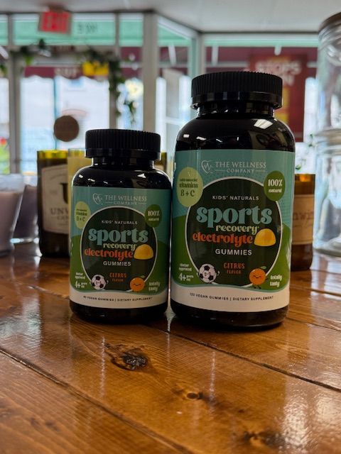 Two bottles of sports recovery electrolyte gummies on a wooden surface.