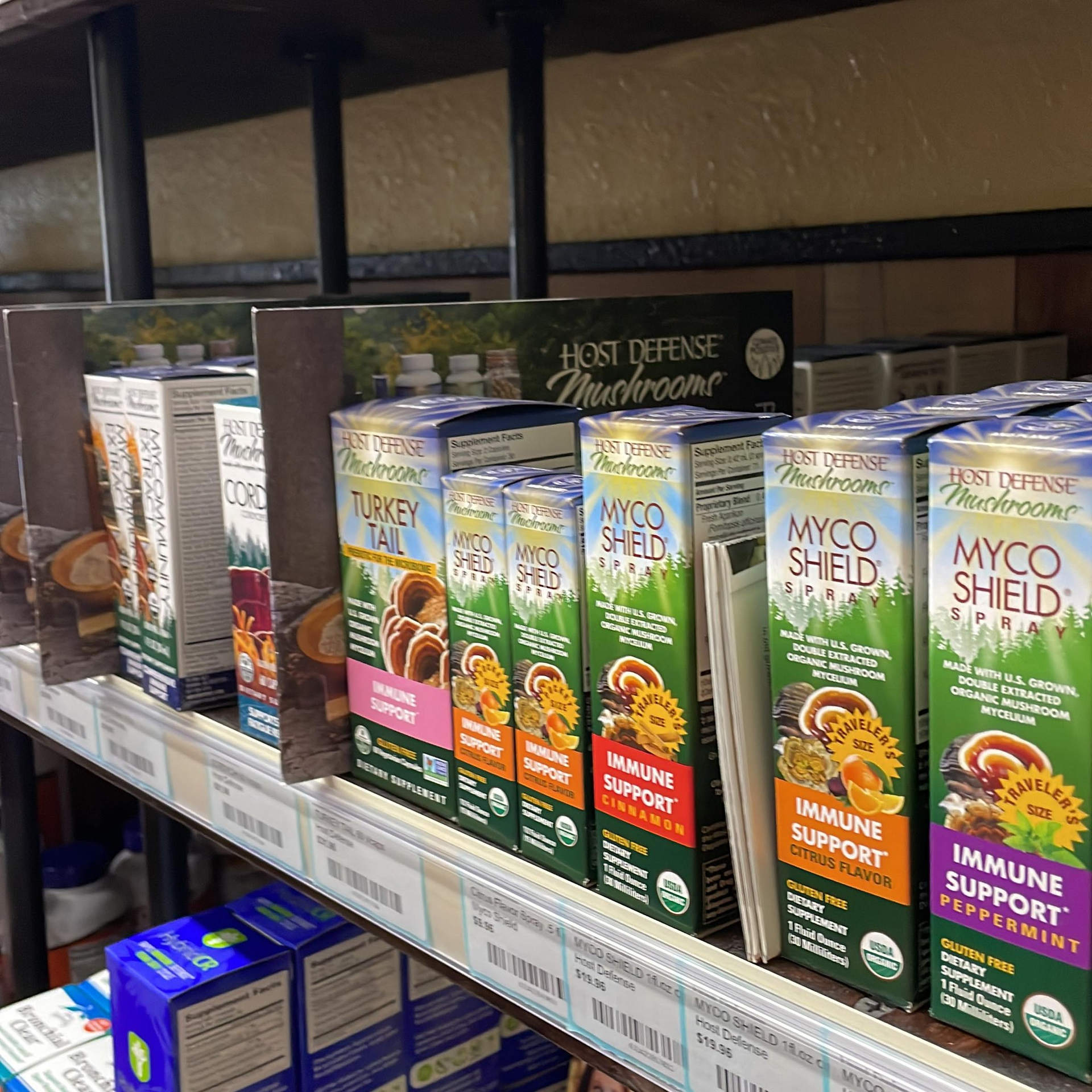 Shelves with mushroom supplement boxes, Host Defense brand, in a store setting.
