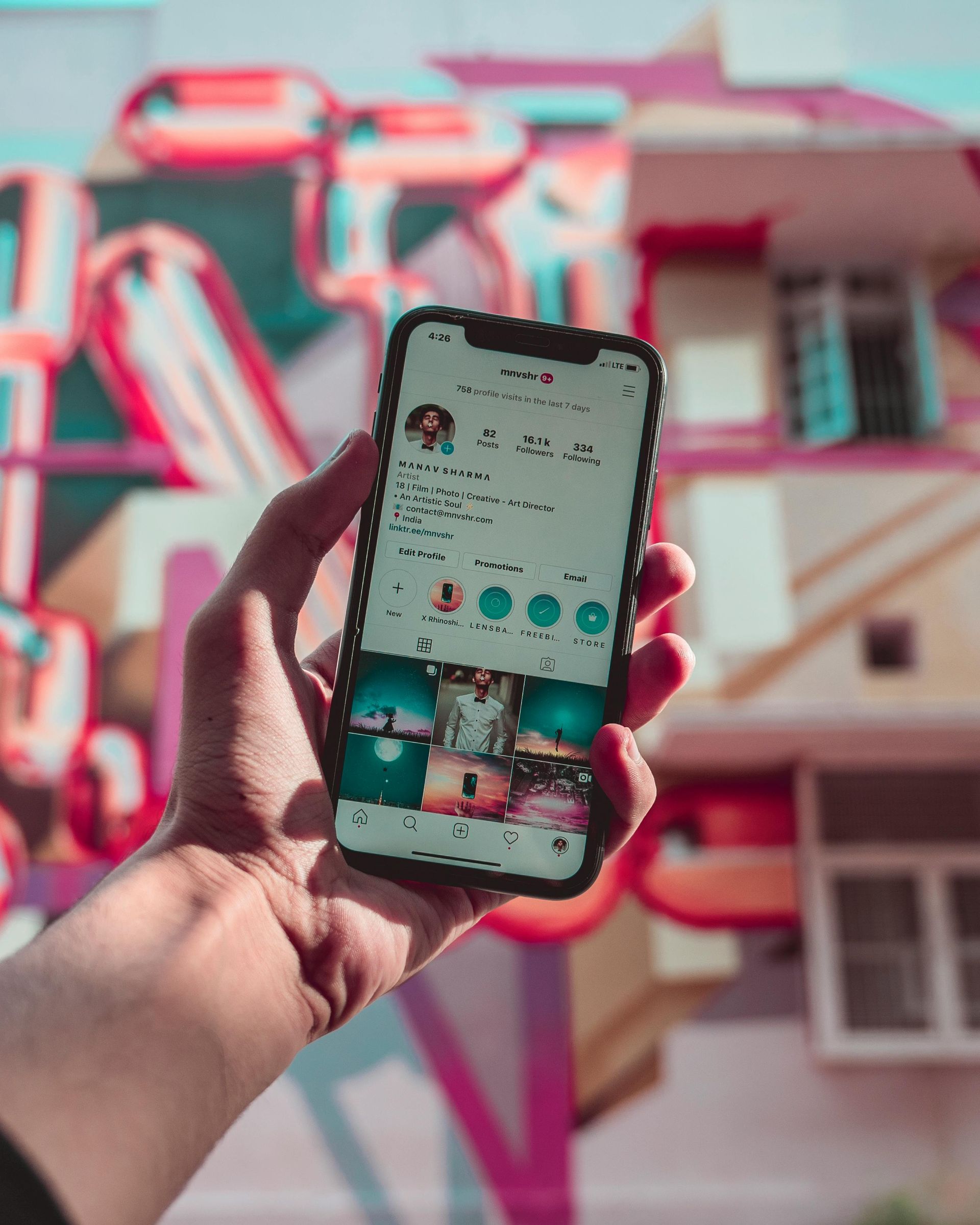 A person is holding a cell phone in their hand in front of a building.