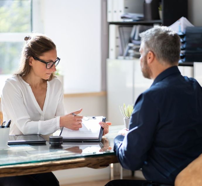 A woman is sitting at a table talking to a man.