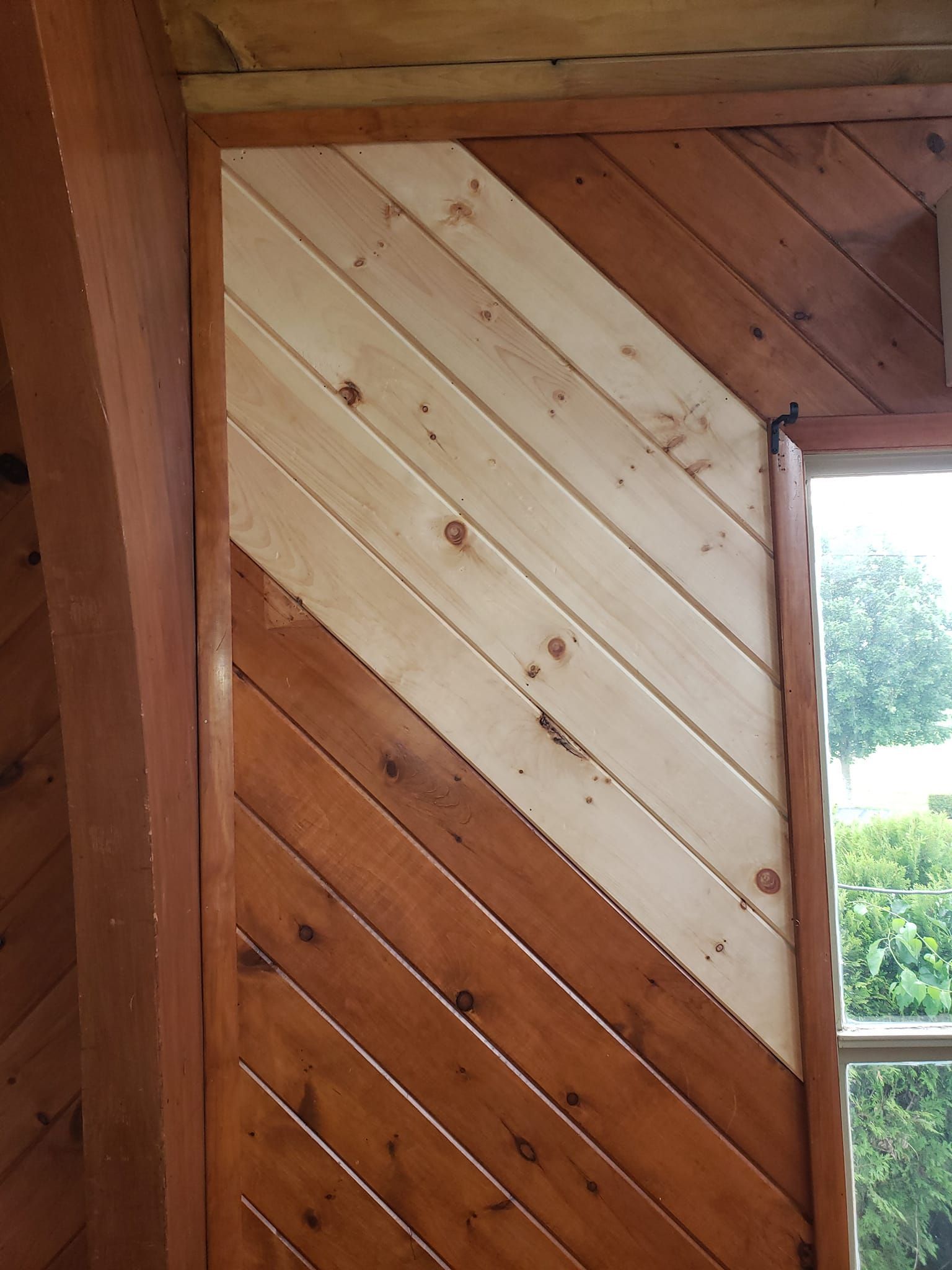 Diagonal wood paneling in two colors, framed in brown wood. Window visible on the right.