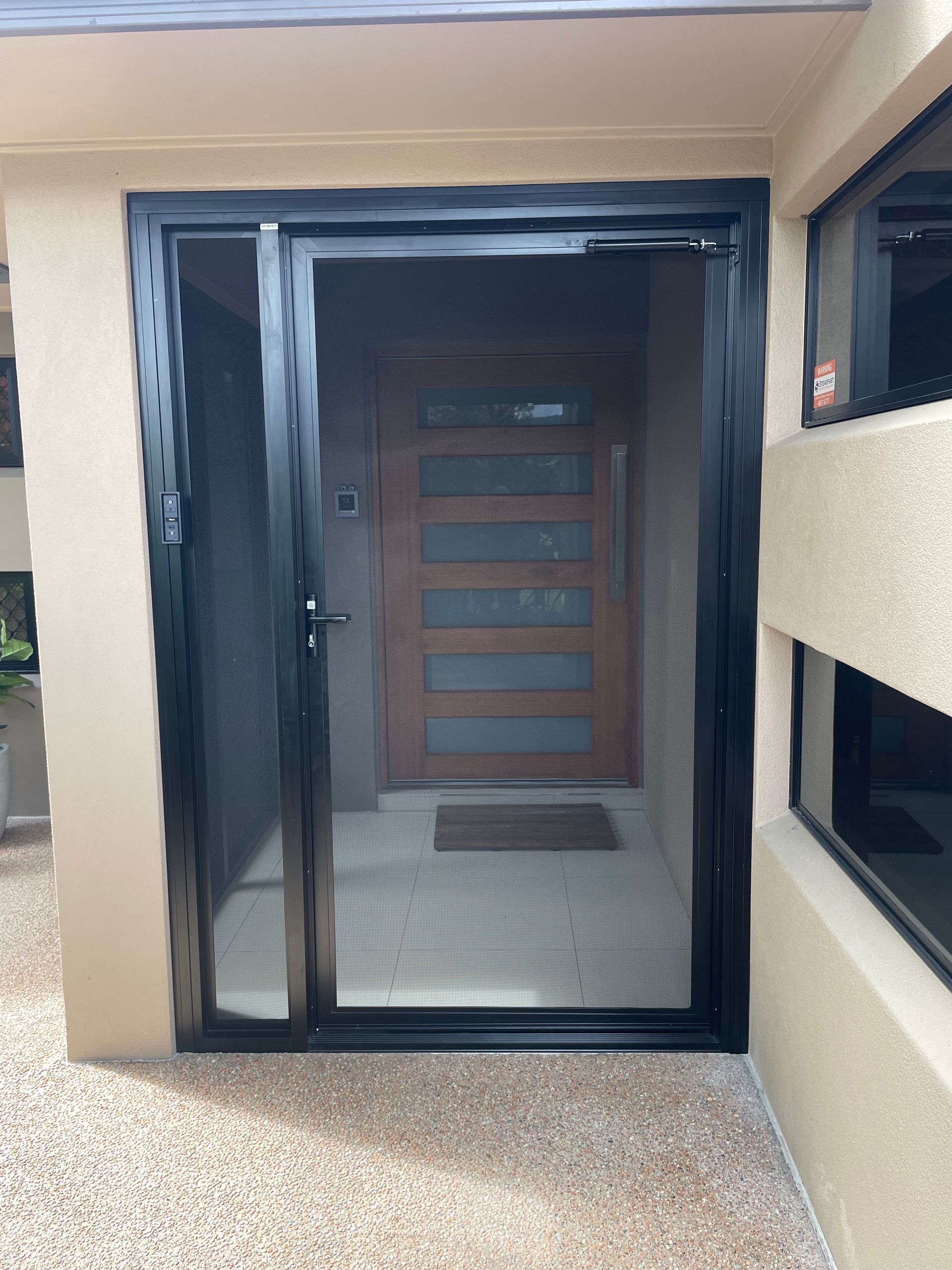Black Security Screen Door Open, Revealing a Wooden Front Door — A1 Security Screens Cairns In Smithfield, QLD