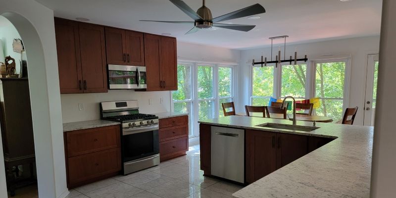 Bright kitchen with wood cabinets, white stove, island, and large windows overlooking greenery