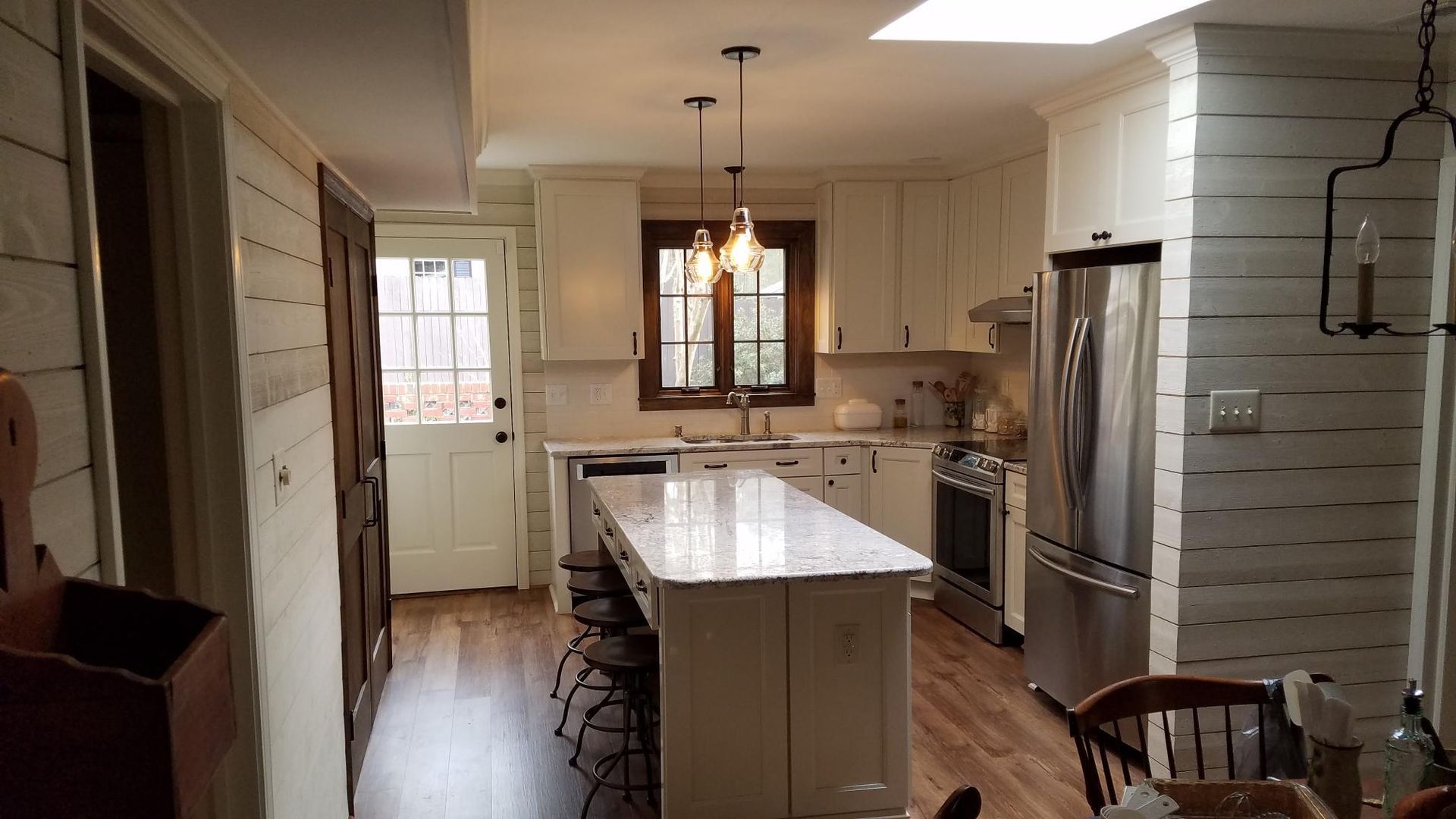 Bright modern kitchen with a large island, pendant lights, white cabinets, and stainless steel appliances