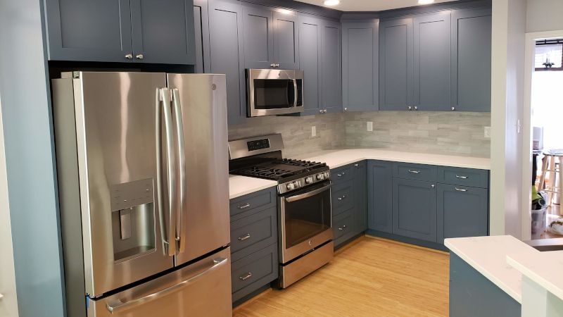 Modern kitchen with blue cabinets, stainless steel appliances, and light wood floors