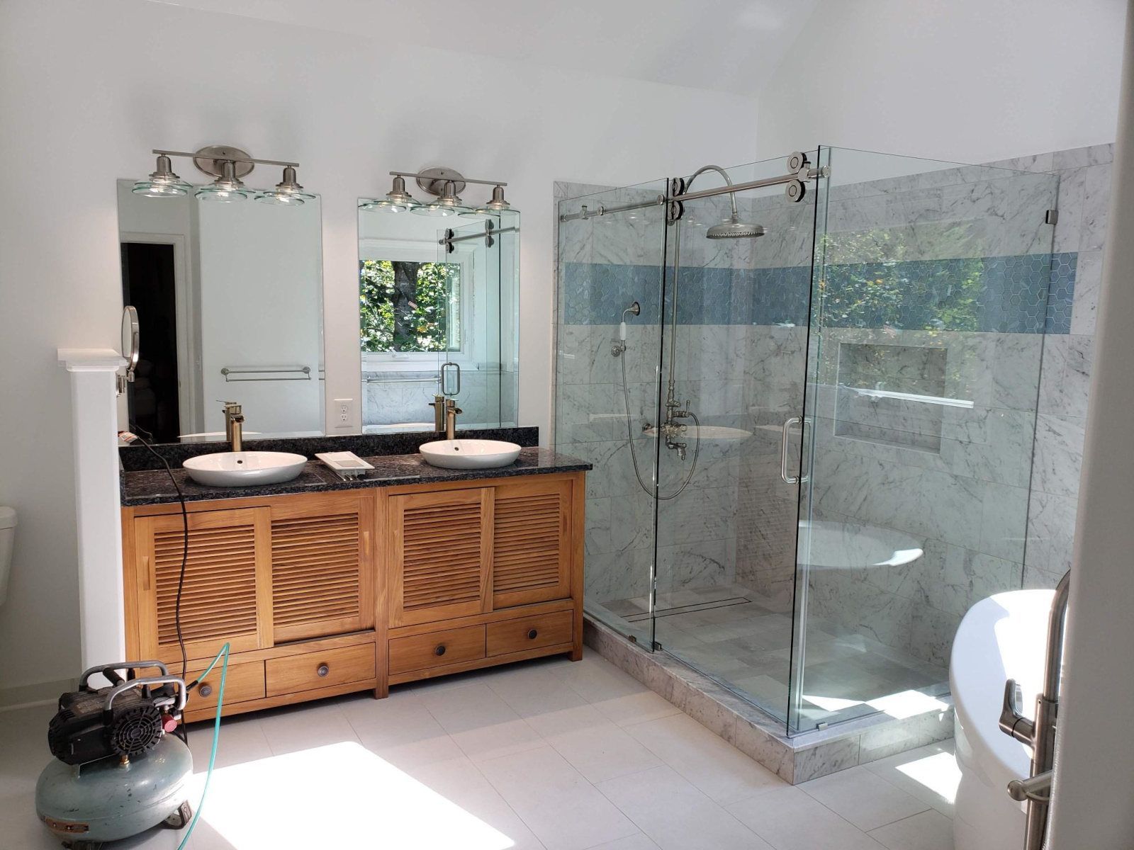 Modern bathroom with double vanity, large mirrors, and glass walk-in shower