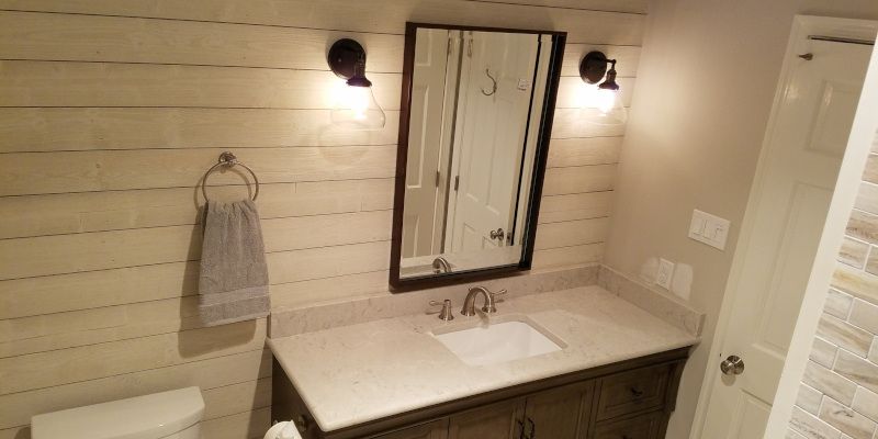 Bathroom vanity with double mirrors, wall sconces, towel ring, and a white countertop sink.
