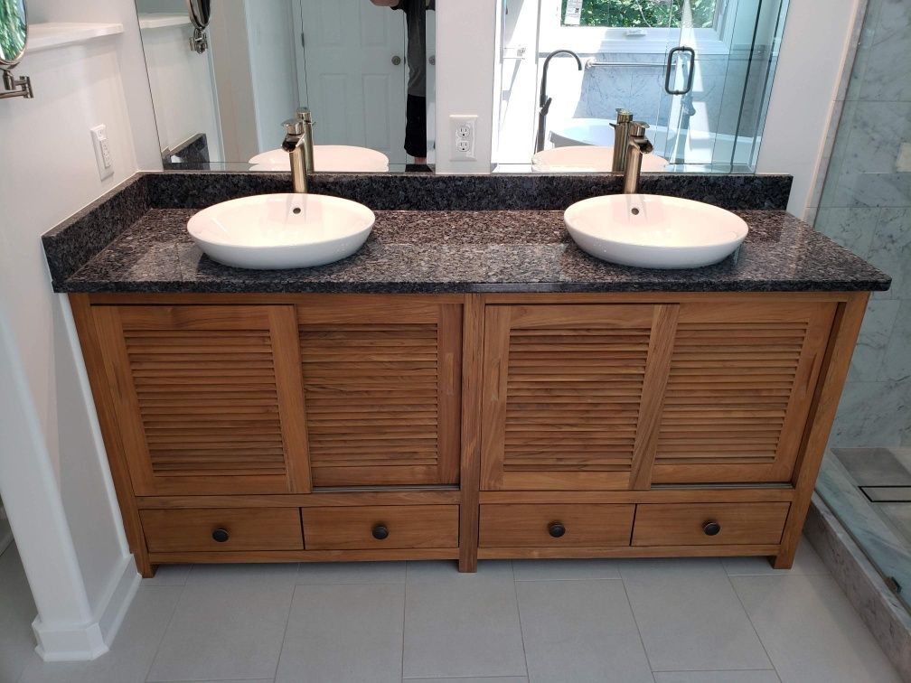 Double vanity with two white vessel sinks, dark granite countertop, and wood cabinets in a bathroom