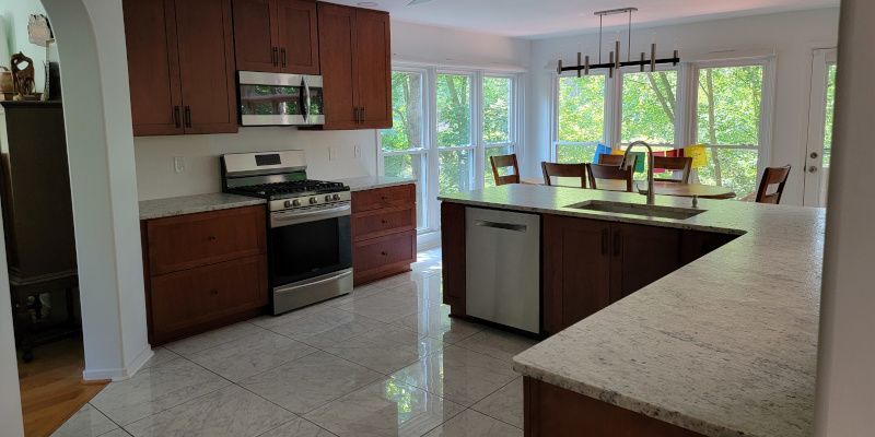 Bright kitchen with dark wood cabinets, stainless stove, and large island by sunlit windows