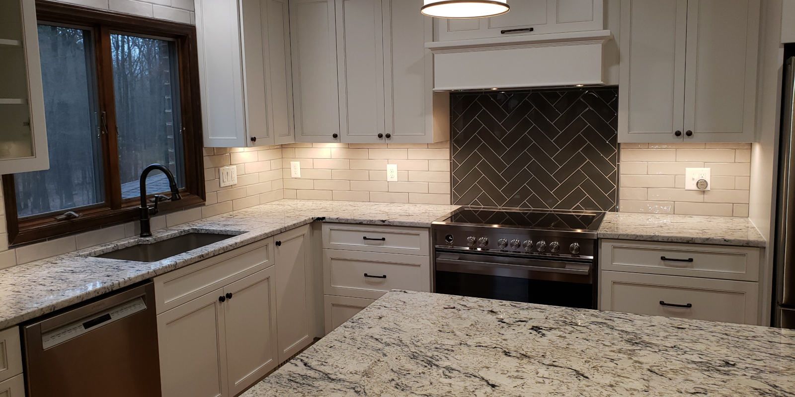 Modern kitchen with granite countertops, gray cabinets, and a stainless steel stove under a tiled backsplash