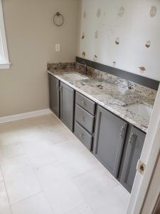 Small bathroom vanity with gray cabinets, white marble countertop, and light tile floor.