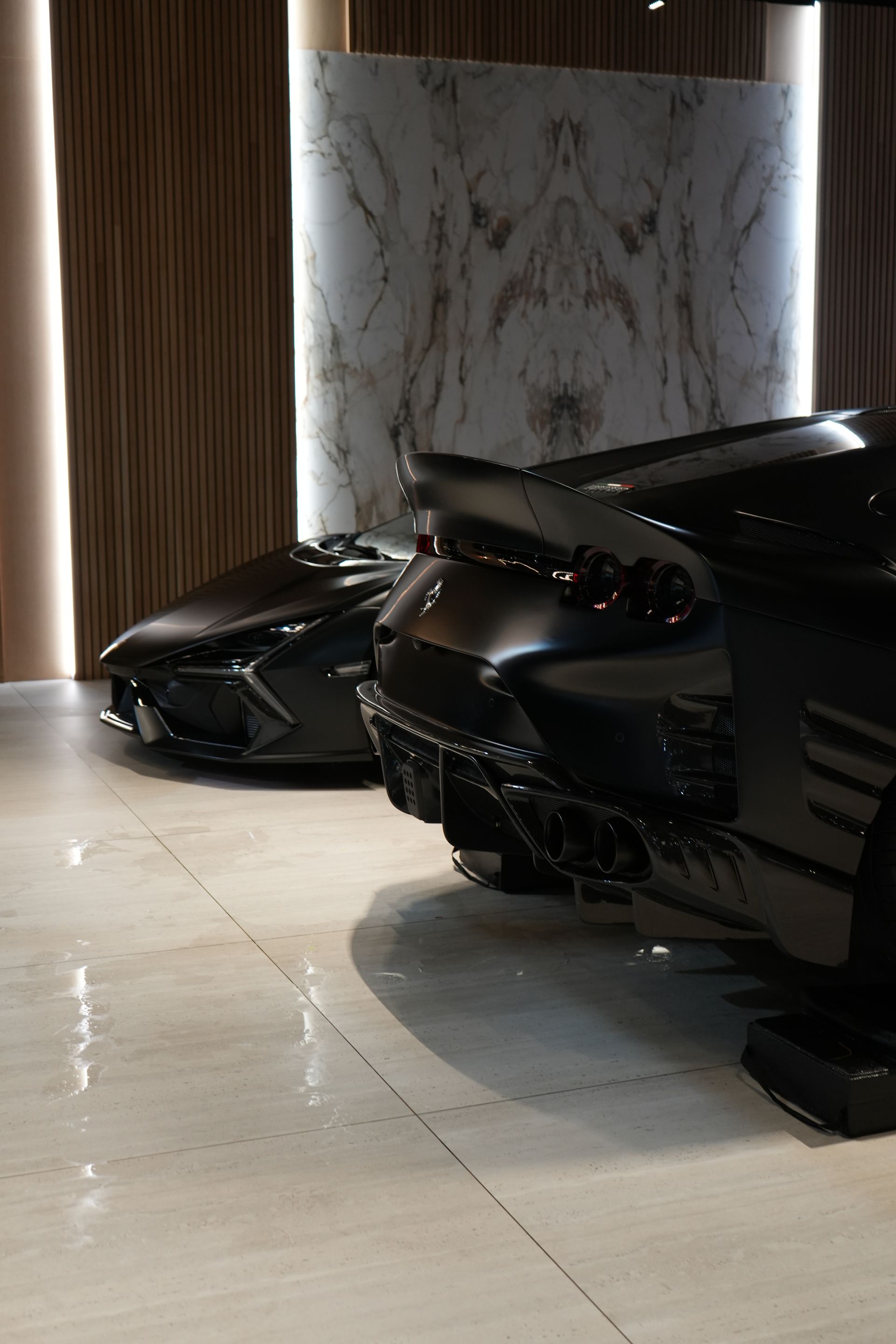 Two black sports cars are parked next to each other in a garage.