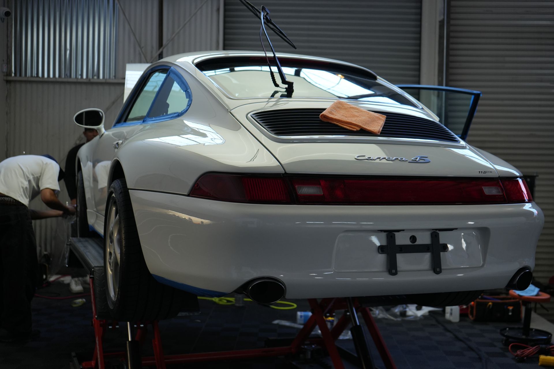 A white porsche is sitting on a lift in a garage.