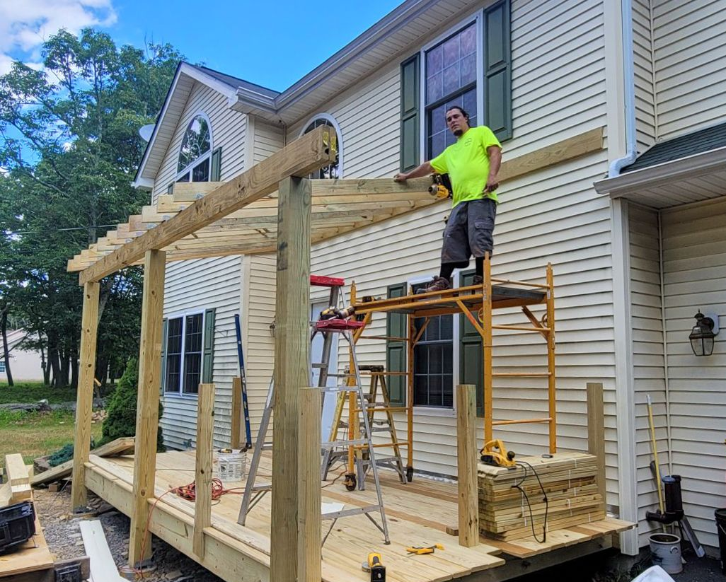 A man is standing on a scaffolding in front of a house.