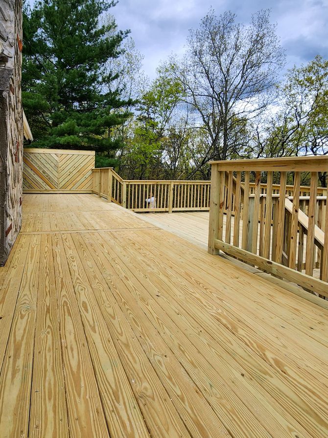 A wooden deck with a railing and trees in the background.