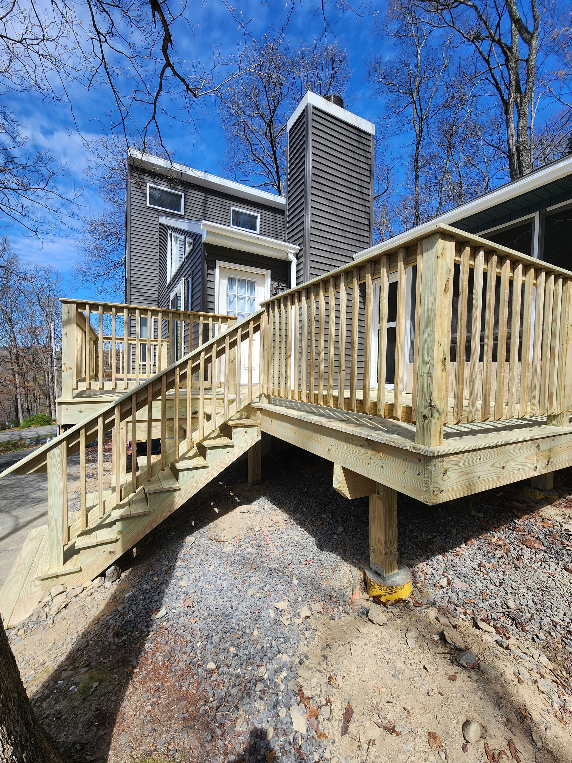 A wooden deck with stairs leading up to it is in front of a house.