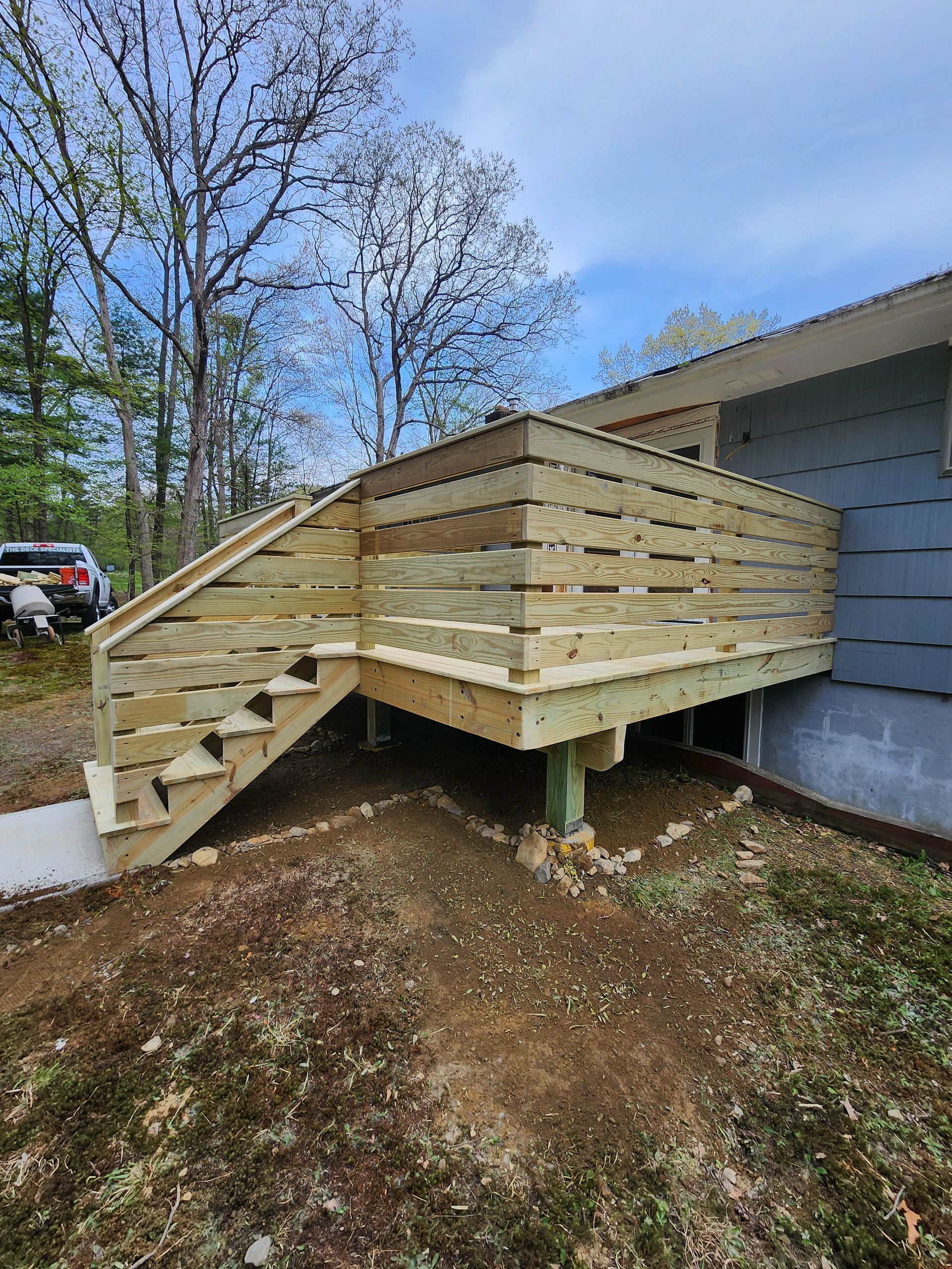 A wooden deck with stairs is being built on the side of a house.