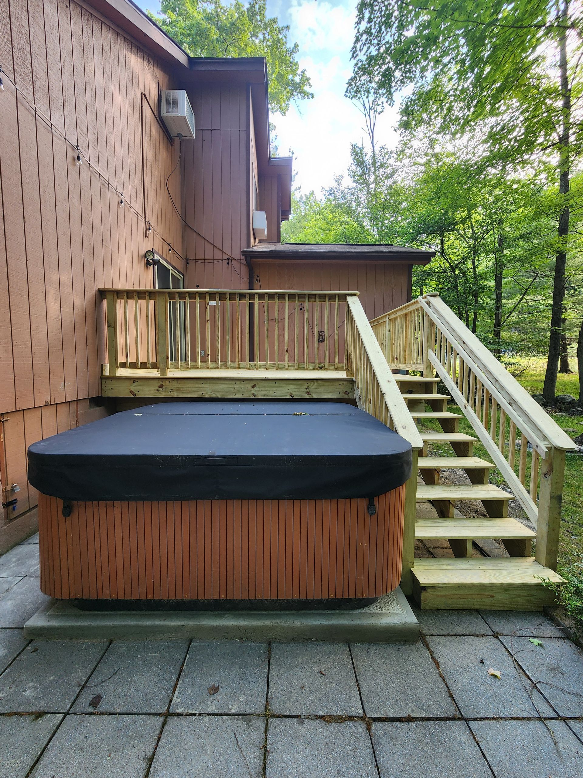 A hot tub is sitting on a deck with stairs leading up to it.