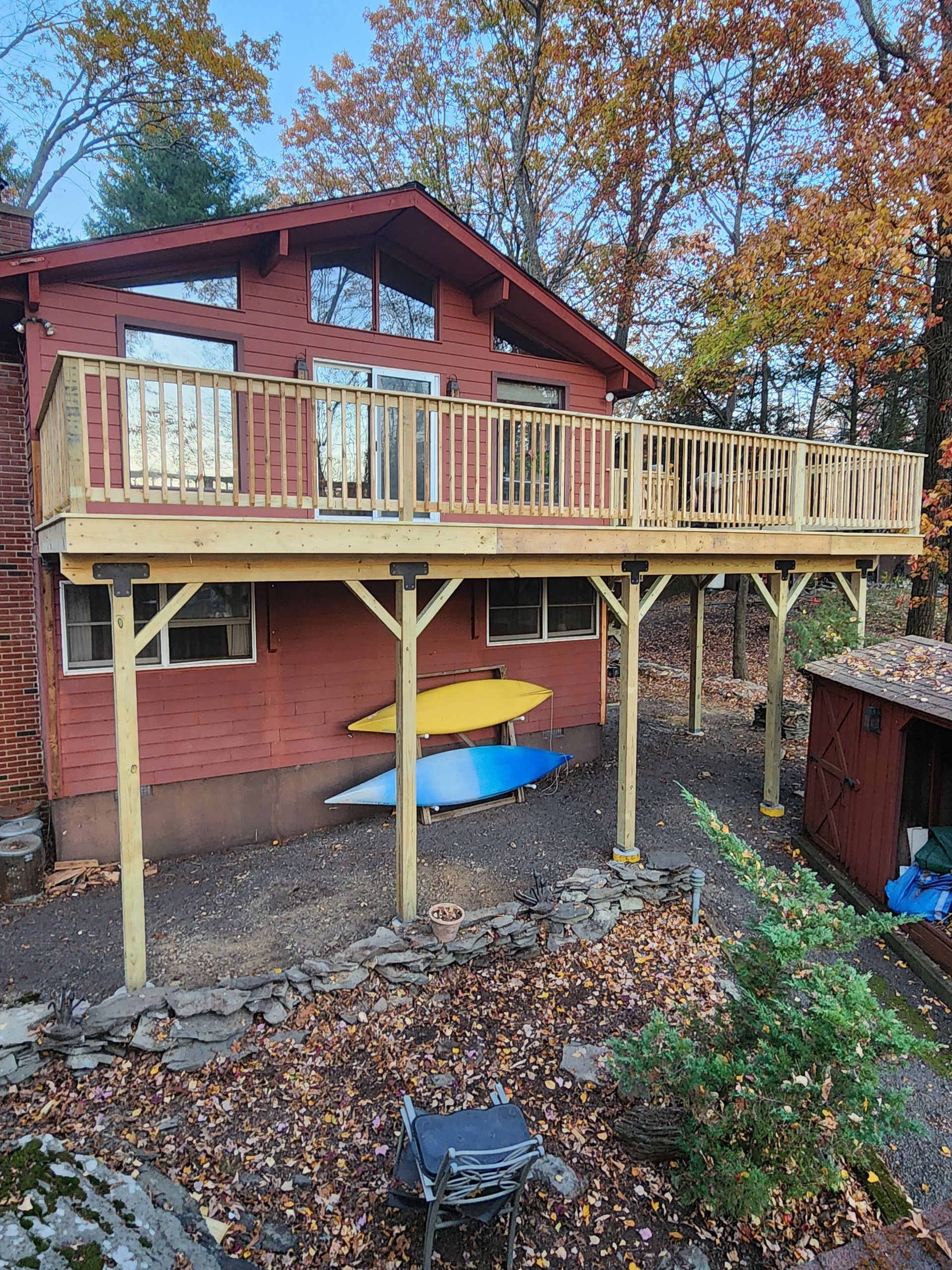 A house with a wooden deck and kayaks on it.