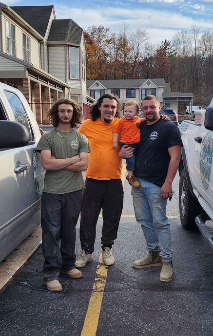 A group of men standing next to each other in a parking lot holding a baby.