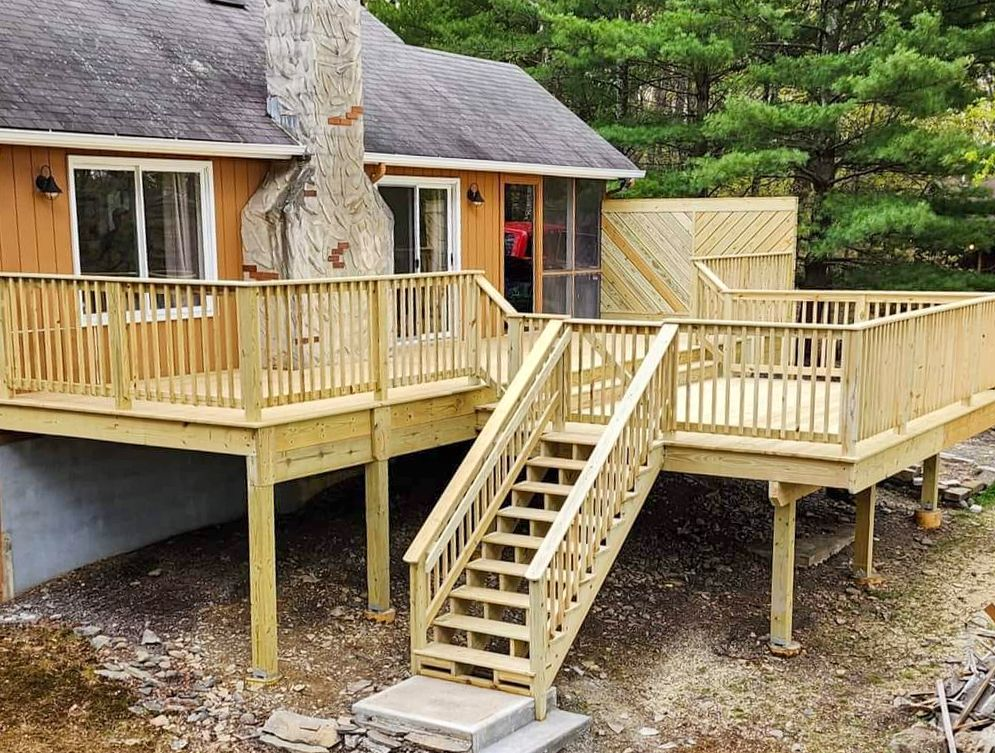A wooden deck with stairs leading up to it is in front of a house.