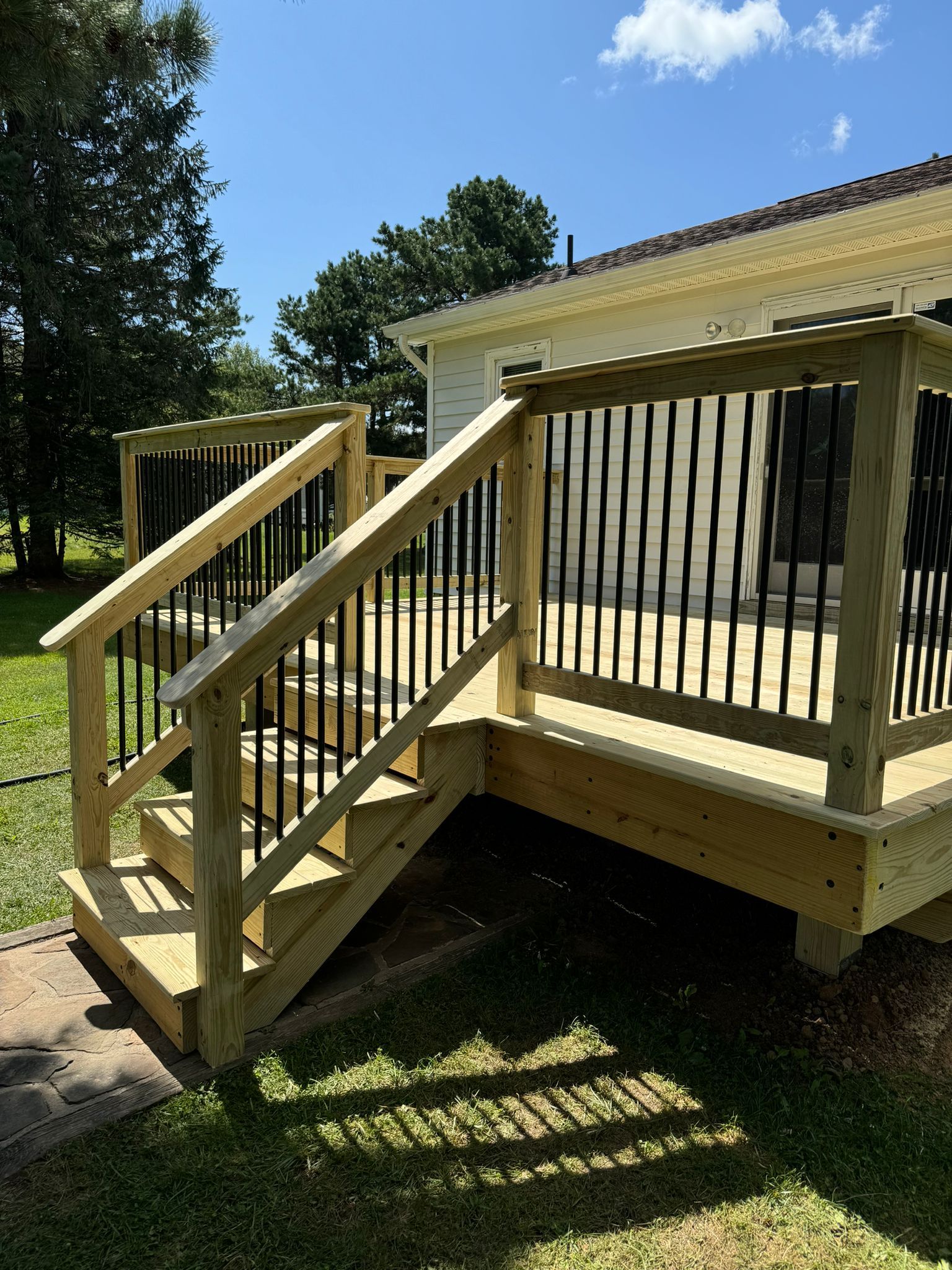 A wooden deck with stairs leading up to it in front of a house.