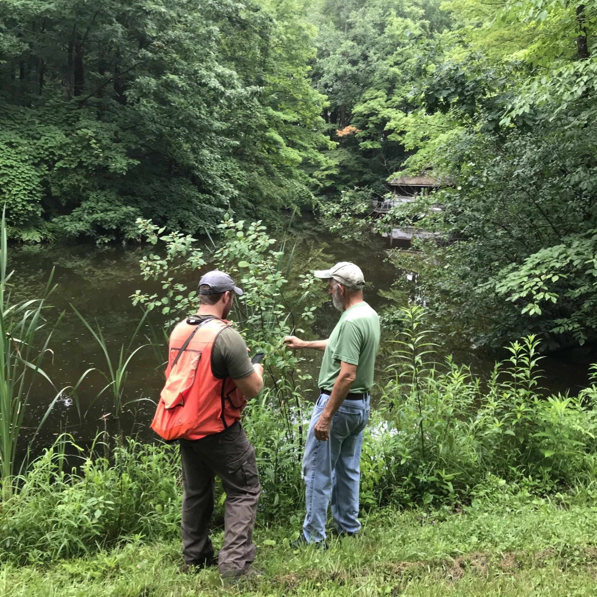 Two men standing next to a river in the woods