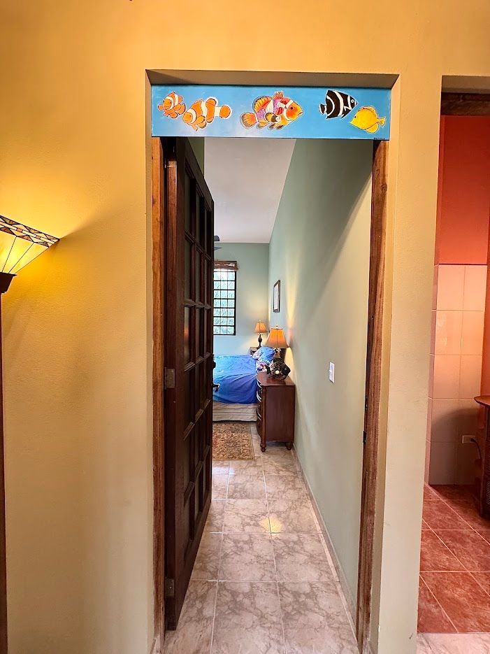 Doorway with wooden door leading to bedroom, decorated with colorful fish above.