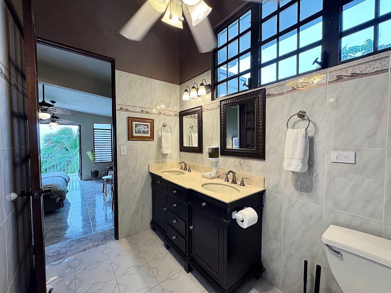 Bathroom with double vanity, tiled walls, and window overlooking a view.