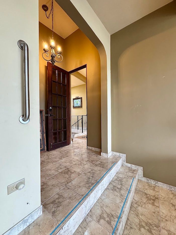 Hallway with marble stairs, door, and handrail. Soft light and neutral colors.