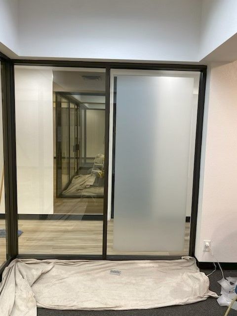 Sliding glass closet doors with mirrored panel in an empty room, floor covered by a tarp