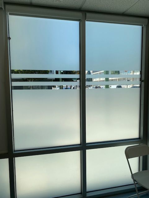 Frosted glass office windows with horizontal frosted bands and a chair partially visible on the right.