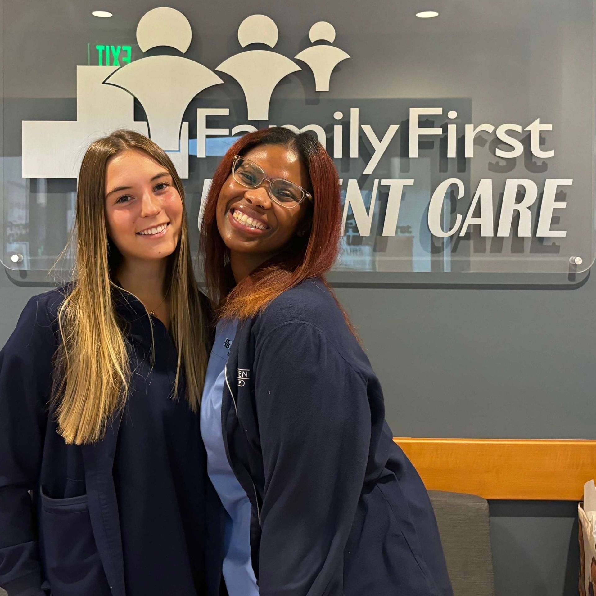 Two medical staff smiling in front of a 