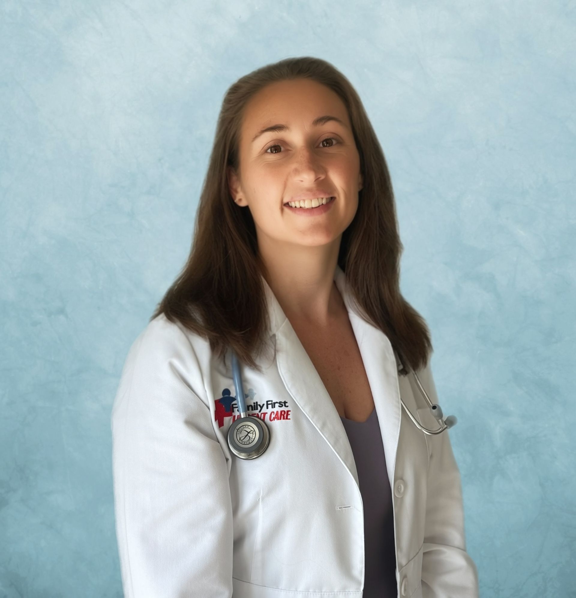 Smiling person wearing a blue patterned jacket and stethoscope in front of a blue background.
