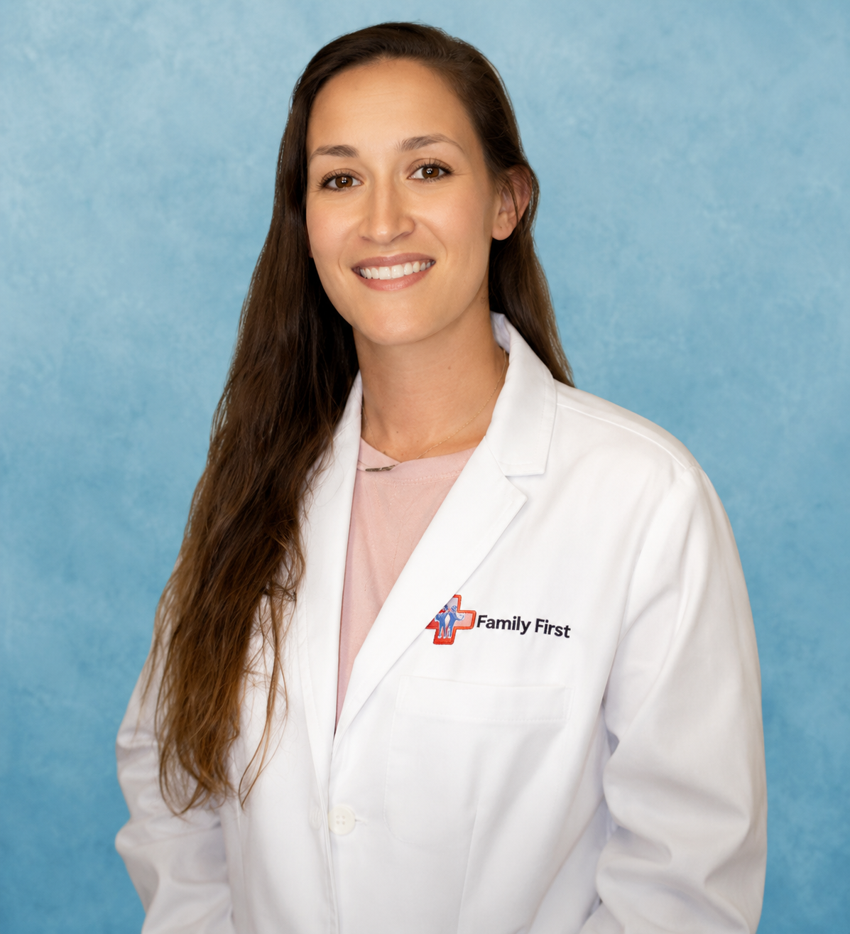 Woman in white lab coat smiles; Family First logo on coat.