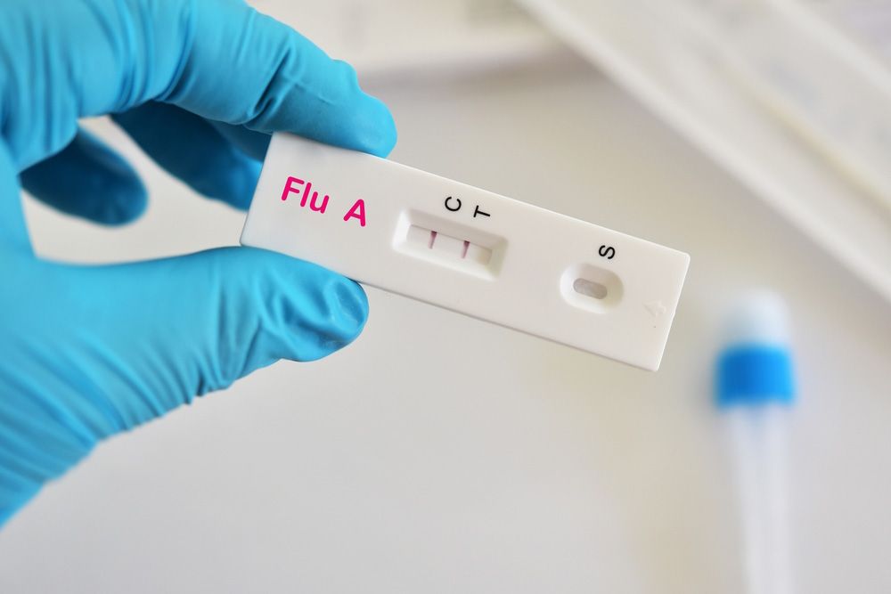 Gloved hand holding a Flu A rapid test cassette with control window