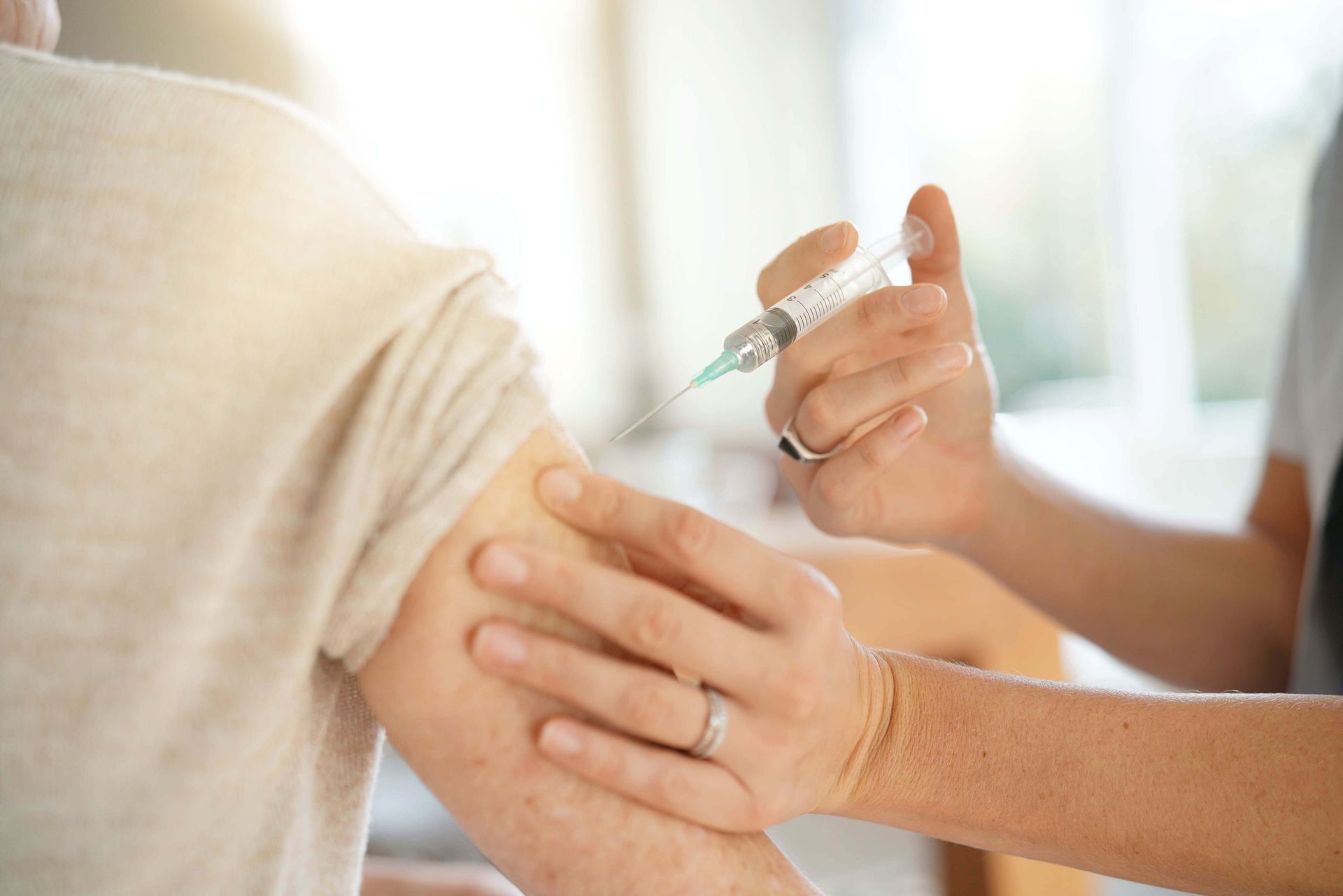 Doctor giving a vaccine injection in a person’s upper arm