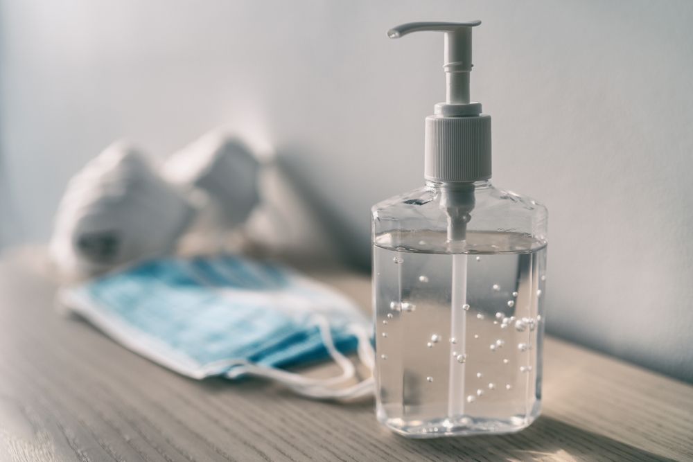 Hand sanitizer bottle with a surgical mask and gloves.