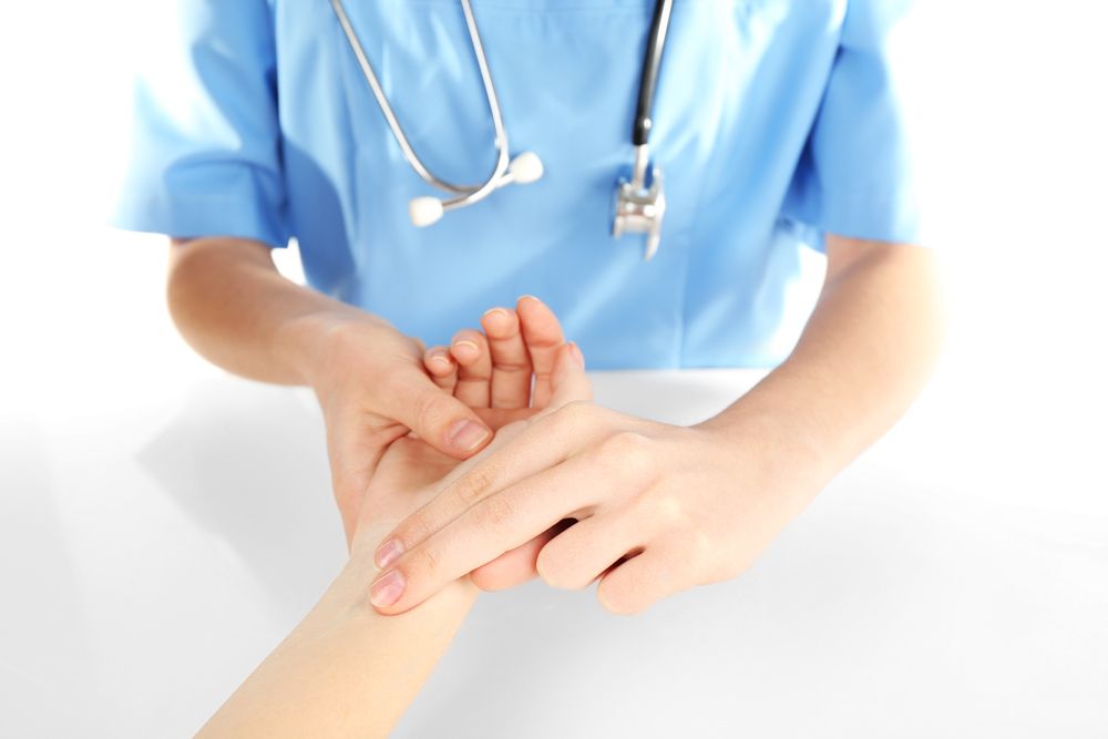 Doctor checking a patient's pulse. The doctor is wearing a blue uniform and a stethoscope.