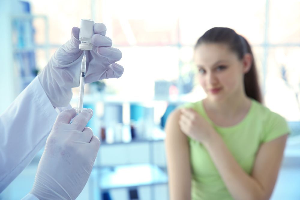 Medical professional preparing to inject a vaccine into a patient's arm. The patient looks on.