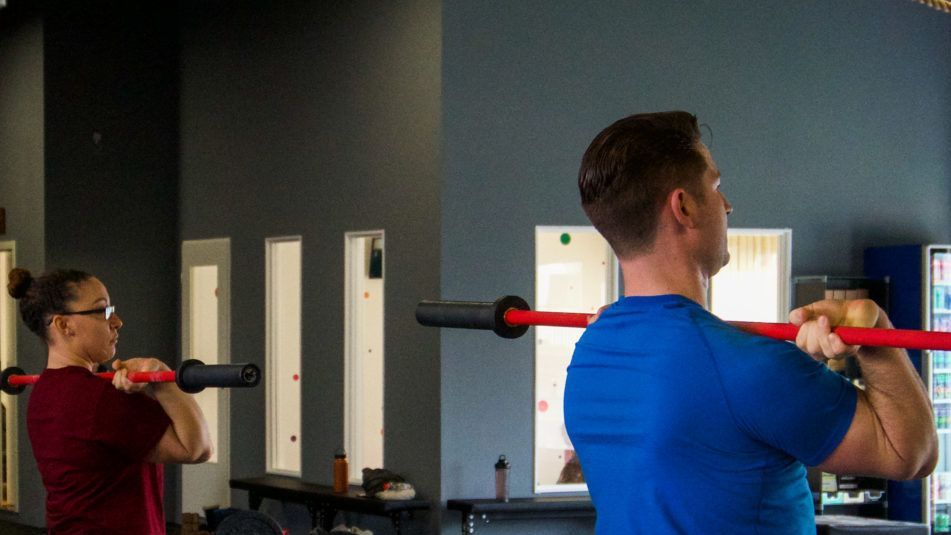 Ein Mann und eine Frau stemmen in einem Fitnessstudio Hanteln.