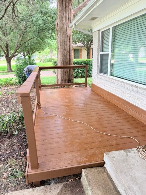 Newly installed brown Trex composite deck with matching railings beside a white brick home in Dallas, TX.