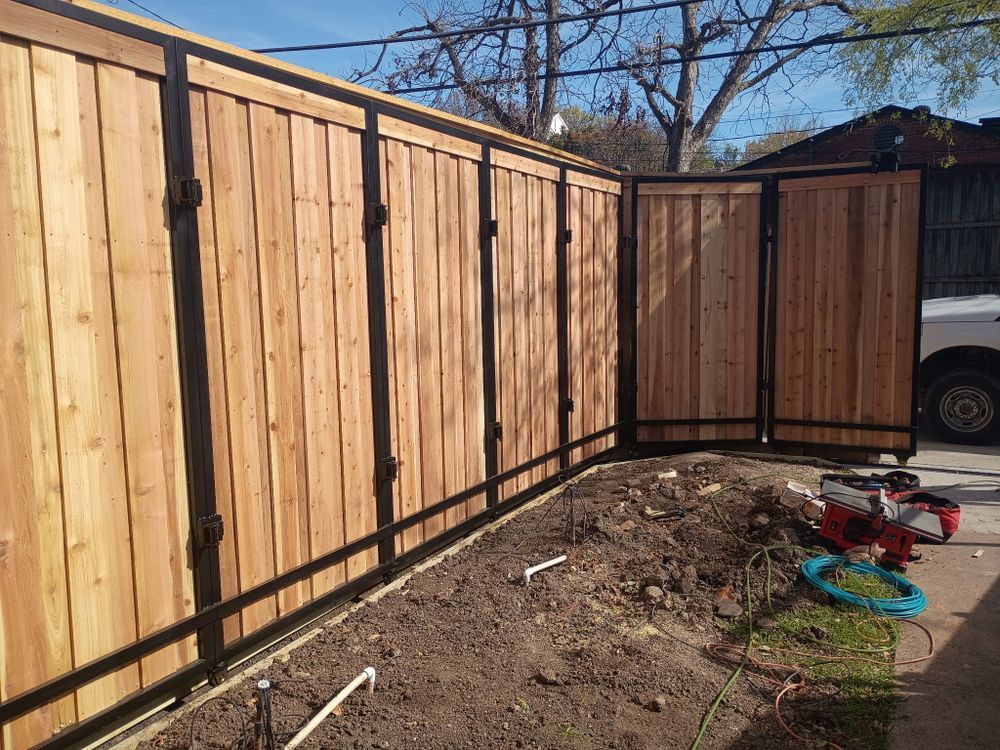 Wooden backyard fence with a curved section, dirt mound, and children’s toys near a garage