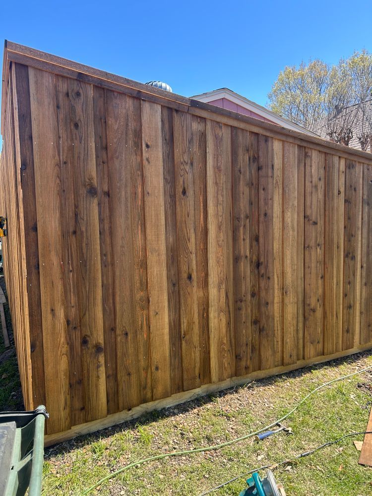 Tall wooden privacy fence along a grassy yard under a clear blue sky